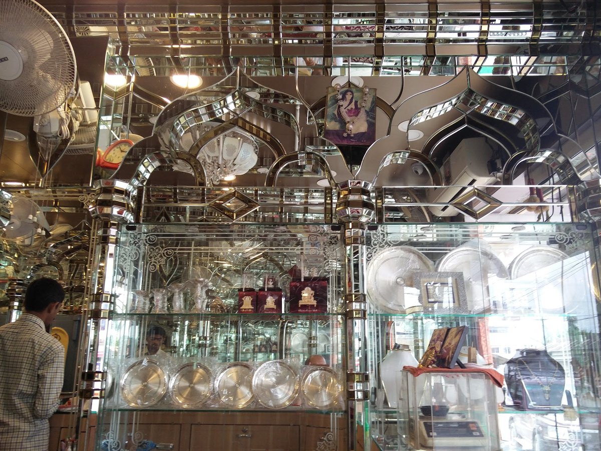 Inside newMATRI JEWELLERY showroom showing silver thali sets, puja items, and mirror showcases